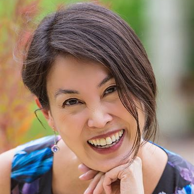 A smiling woman with her chin on her hand