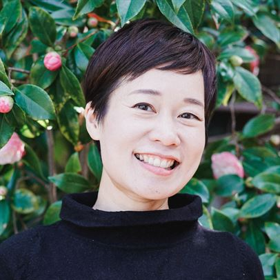 A smiling woman in front of a bush